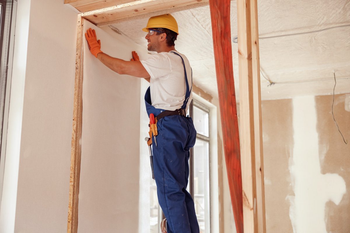 Male worker hanging wallpaper on the wall