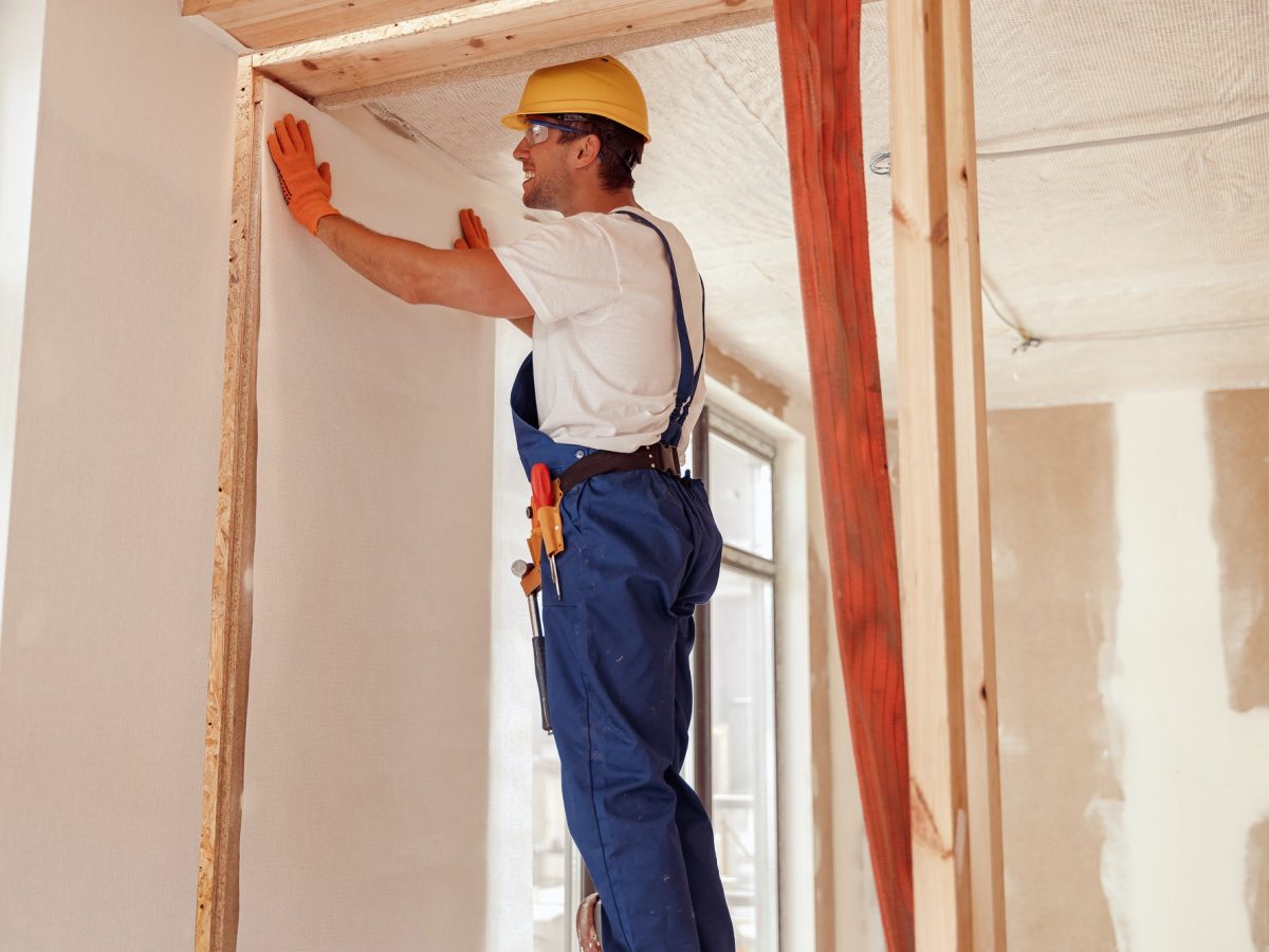 Male worker hanging wallpaper on the wall